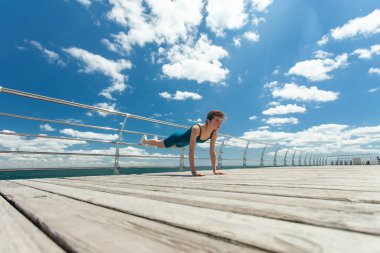 Parlak güneşli bir günde, sette, mavi gökyüzü ve bulutlarla antrenman yapmadan önce ısınmaya hazır bir kadın. Geniş açı