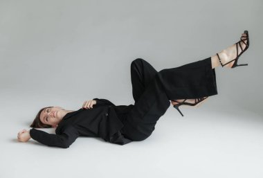 Gri arka planda şık giyinmiş genç bir kadın.