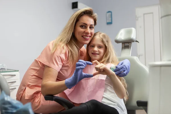 Female Dentist Little Girl Patient Show Heart Fingers While Looking — Stock Photo, Image