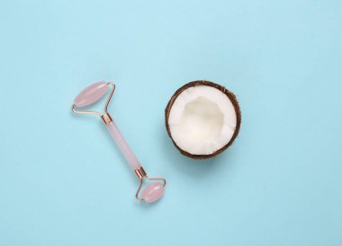 Yüz masajı silindiri ve mavi arka planda hindistan cevizi. Doğal kozmetik konsepti