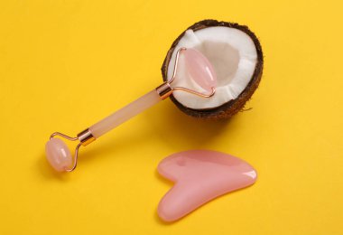 Yüz masajı silindiri ve sarı arka planda hindistan cevizi. Doğal kozmetik konsepti. Cilt bakımı