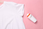 Antiperspirant válec a bílé tričko na růžovém pozadí. Antiperspirant bez skvrn. Horní pohled