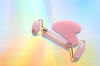 Renkli holografik yüzeyde yüz masajı silindiri ve taş 