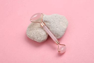 Pembe arka planda doğal taşı olan yüz masajı silindiri.