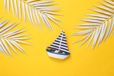 Yat modeli ve sarı arkaplanda beyaz palmiye yaprakları