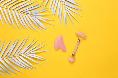 Sarı arka planda beyaz palmiye yaprakları olan yüz masajı silindiri. Güzel yerleşim
