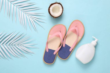 Beach vacation, tripic background. Flip flops with white palm leaves, cream bottle and coconuts on white background. Summer flat lay. Top view
