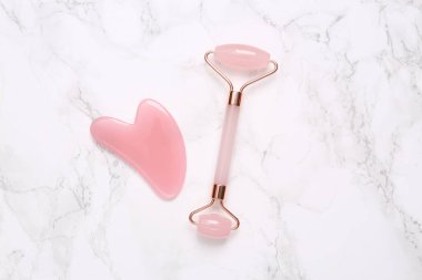 Mermer arka planda yüz silindiri ve gua sha taş masajcısı