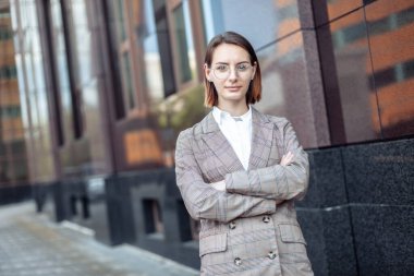 Şehirdeki bir iş binasının arka planında kendine güvenen modern bir iş kadınının portresi.