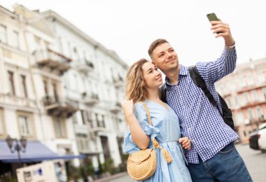 Aşık genç bir çift şehirdeki bir akıllı telefondan selfie çekiyor. Birlikte zaman geçirme kavramı
