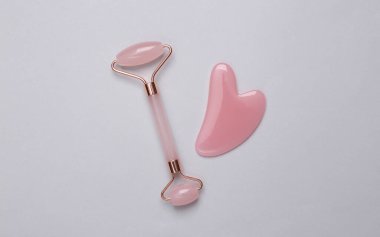 Yüz silindiri ve gri arka planda gua sha taş masaj aleti. Üst görünüm