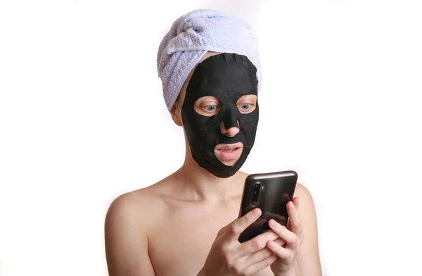 Młoda Atrakcyjna Kobieta Czarną Maską Kosmetyczną Oczyszczającą Przy Użyciu Smartfona — Zdjęcie stockowe