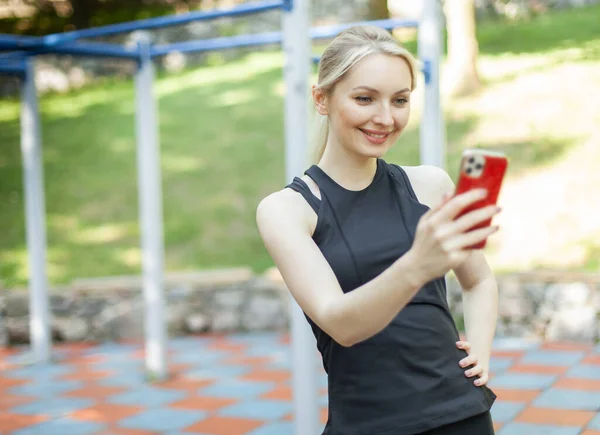 Spor Giyim Bölümünde Gülümseyen Sarışın Kadın Spor Sahasındaki Telefon Ekranına — Stok fotoğraf