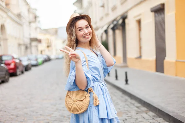 Şapkalı ve elbiseli hoş genç bir kadın Avrupa caddesinde eğleniyor.