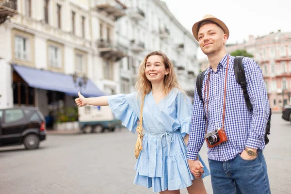 Genç bir çift Avrupa caddesinde bir araba yakalıyor. Ortak seyahat, otostop.