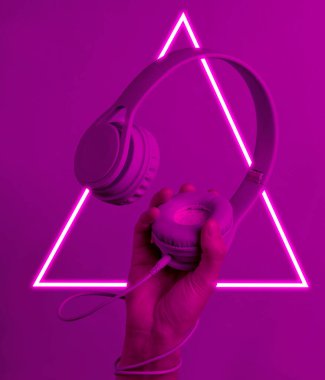 Elle sarılmış kablo kulaklık tutuyor. 80 'lerin sentetik dalgası ve parlayan üçgen fütüristik estetiği. Eski moda soyutlama kavramı