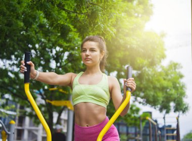 Spor sahasında egzersiz makineleri üzerinde egzersiz yapan çekici atletik kadın.