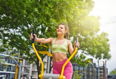 Spor sahasında egzersiz makineleri üzerinde egzersiz yapan çekici atletik kadın.
