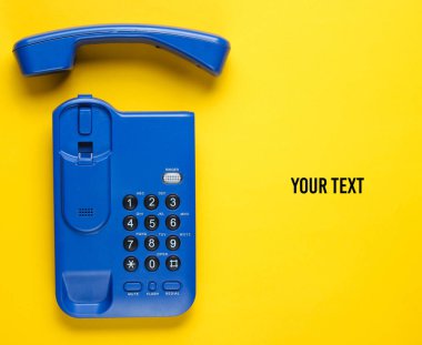 Sarı arka planda cep telefonu olan kablosuz ofis telefonu. Üst Manzara. Boşluğu kopyala