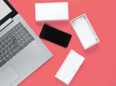 Boksu açma, tekno blog yazma kavramı. Yeni akıllı telefonlu bir kutu, pembe arka planda dizüstü bilgisayar..