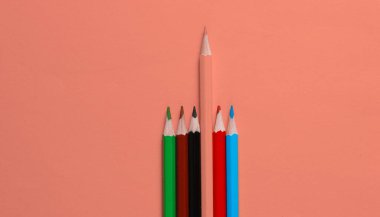 Mercan zemin üzerinde renkli kalemler. Eşsizlik konsepti. Üst görünüm