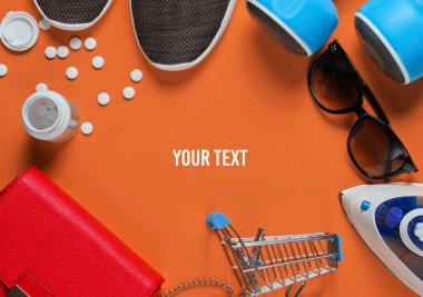 Satın alma konsepti. Turuncu arka planda birçok farklı nesne. Üst görünüm