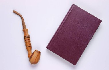 Eski tarz. Eski kitap, beyaz arka planda pipo içmek. Üst görünüm, minimalizm