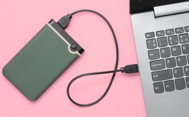 Pembe arka plandaki bilgisayara bağlı harici sabit disk. Üst görünüm
