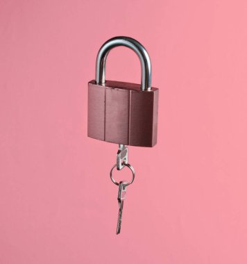 Metal lock with key on vanilla pink background