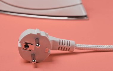 Iron with electric plug on vanilla background close up