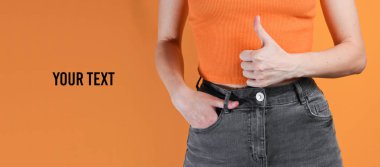 Woman showing thumb up gesture over orange background. Crop photo, studio shot. Copy space