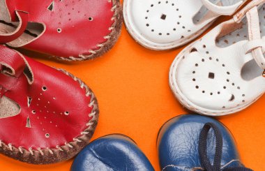 Turuncu arka planda bir sürü çocuk deri ayakkabısı var.