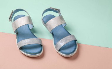 Pastel mavi-pembe arka planda deri kadın sandaletleri. Yaz ayakkabıları