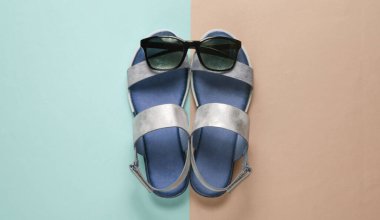 Creative summer beach flat lay. Leather women's sandals, sunglasses on colored background. Top view