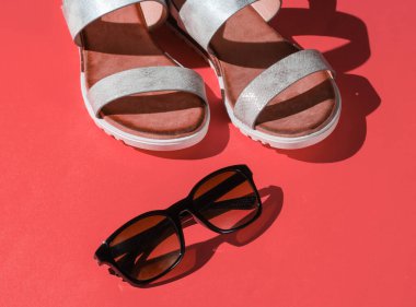 Fashionable women's sandals with sunglasses on pink background. Summer accessories