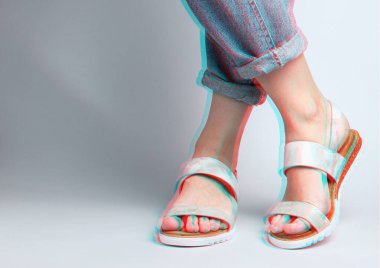 Mavi kotlu kadın bacakları ve beyaz arka planda son moda deri sandaletler. Arıza etkisi. Minimalist moda çekimi