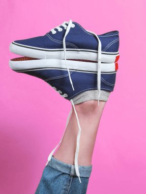 Yaratıcı moda çekimi. Kalkmış kadın bacağının topuğunda pembe arka planda hippi ayakkabıları..