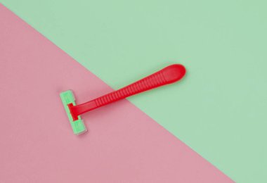 Minimalist güzellik konsepti. Renkli arka planda kırmızı plastik jilet. Üst görünüm