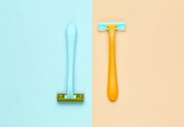 Minimalist güzellik konsepti. Mavi sarı pastel arka planda iki plastik jilet. Üst görünüm