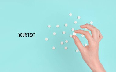 Mavi arka planda beyaz hapları tutan bir kadın. Tıbbi minimalist konsept. Boşluğu kopyala