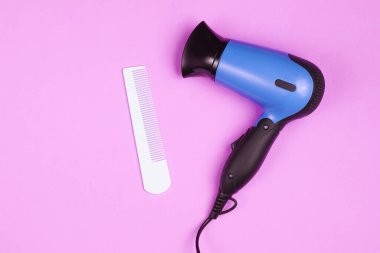 Minimalist güzellik ve moda hala hayat. Saç kurutma makinesi ve pembe arka planda tarak. Üst manzara, düz uzanma