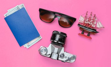 Gezgin aksesuarları, pembe arka planda retro kamera. Sahilde gezi, tatil. Yaz minimalist geçmişi. Düz yatay turizm alegorisi