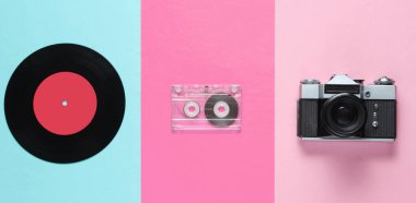 Retro natürmort hayat, 70 'ler. Vinil plak, ses kaseti ve pastel arka planda film kamerası. Üst Manzara. Düz yatıyordu