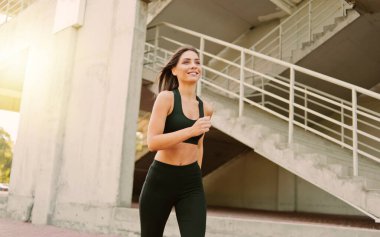 Spor giyim sektöründe şehir ortamında koşan çekici bir kadın. Spor, sağlıklı yaşam tarzı.