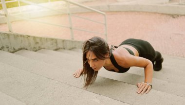 Young fit woman doing push up exercise from stairs outdoors in an urban environment