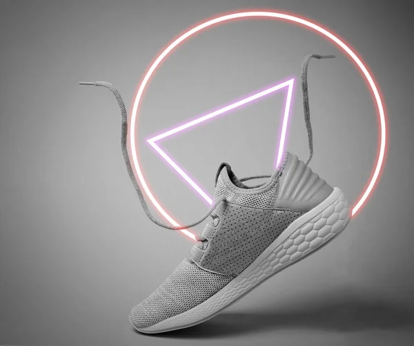 Running sports shoes with flying laces. 80's synth wave and retrowave glowing circle futuristic aesthetics. Old fashioned abstraction concept