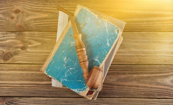 Ahşap arka plandaki eski kitap yığınının üzerinde sigara piposu içmek