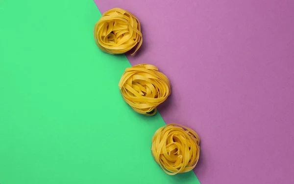 Minimalism Italian Food Concept Raw Tagliatelle Noodles Green Purple Background — Stock fotografie