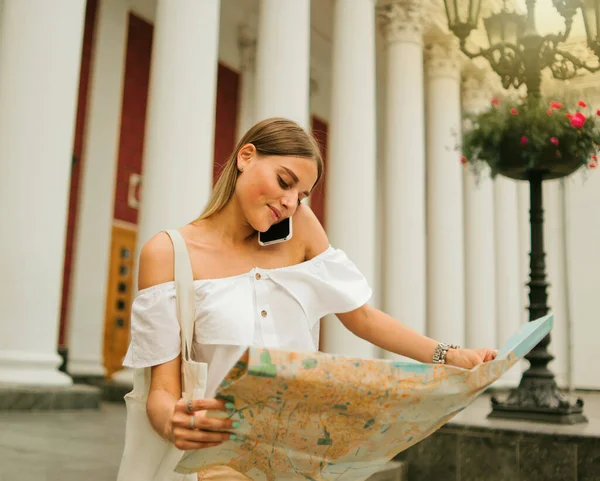 미모의 관광객들은 지도를 탐험하고 기둥들의 배경을 배경으로 통화를 — 스톡 사진