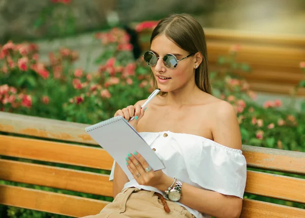 Piękna Młoda Kobieta Letnich Ciuchach Okularach Przeciwsłonecznych Trzymająca Smartfona Pisząca — Zdjęcie stockowe